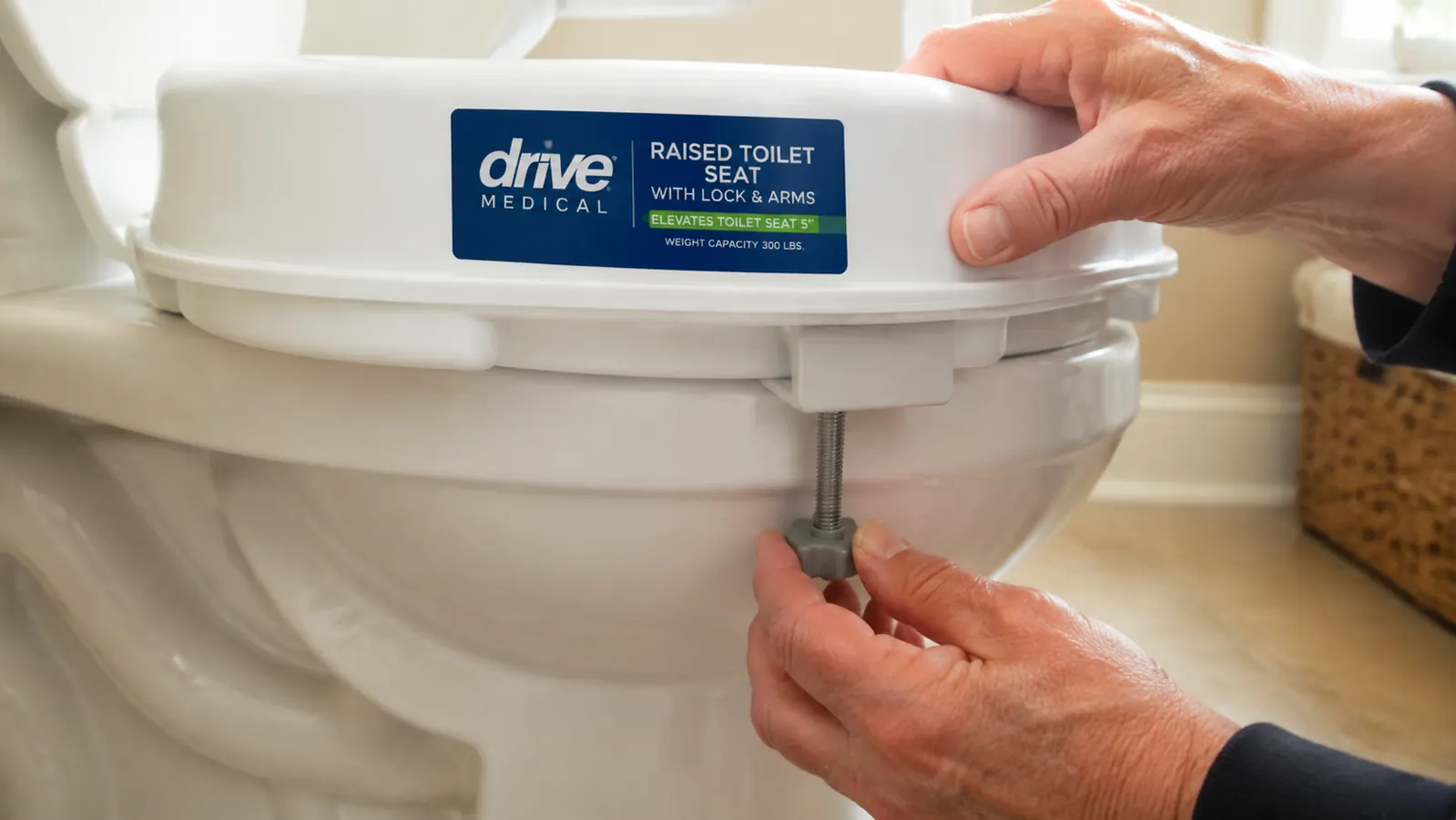 Close-up of a hand tightening the locking bracket on a raised toilet seat